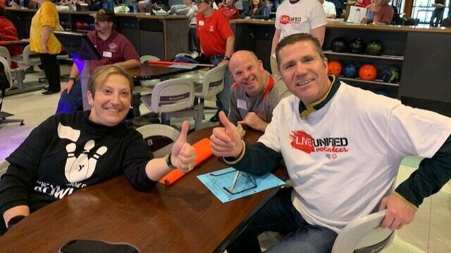 AE Cares volunteers giving a thumbs up at an event.