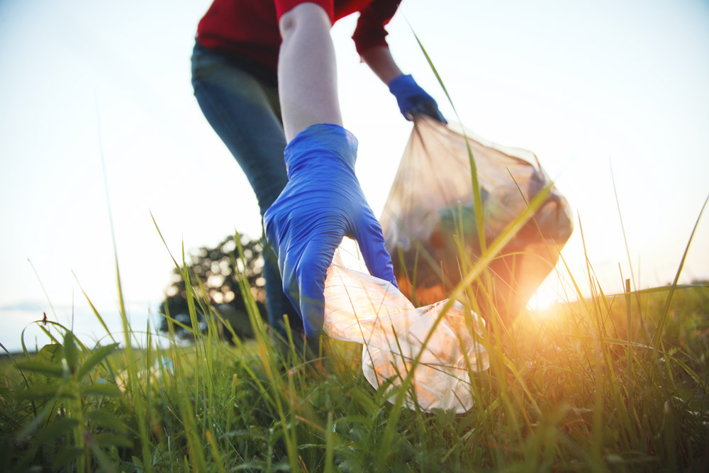 A volunteer in gloves collecting litter.