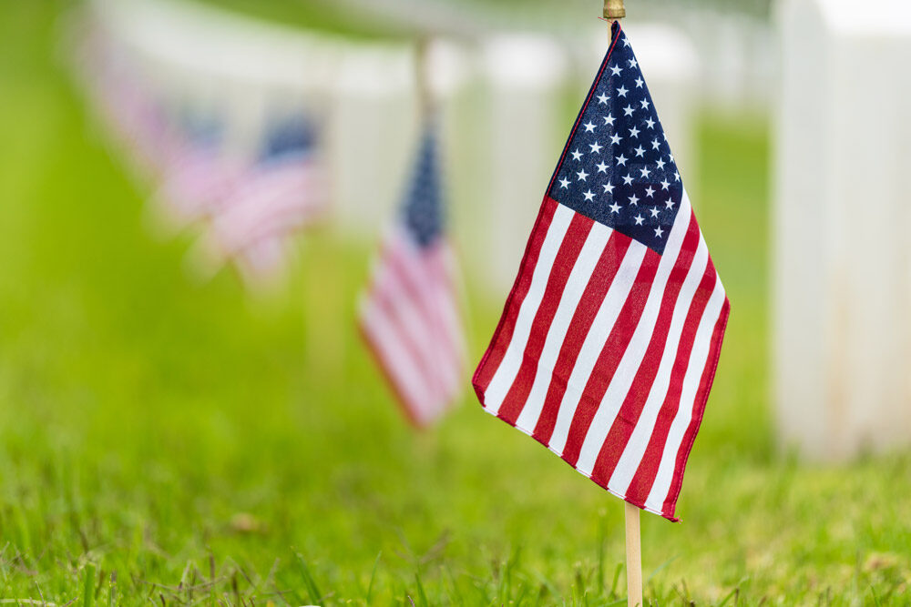AE Cares volunteers placing remembrance flags at a Veteran's gravesite.