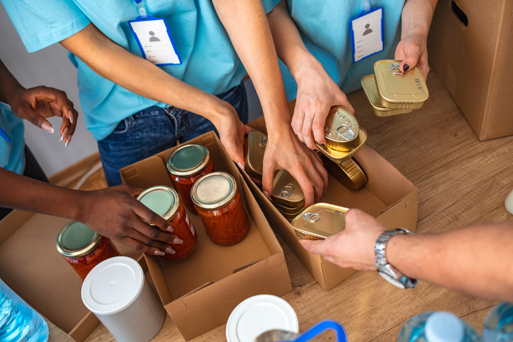 Volunteers packing tinned food into boxes.