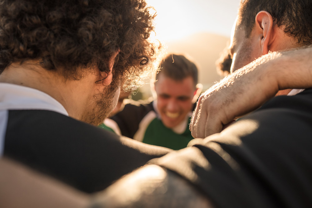 A team huddled together, arms around one another.